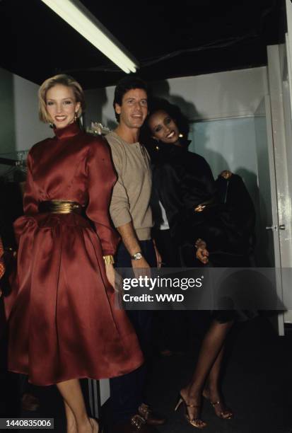 Two models, wearing silk satin organza dresses with gold belts, with Calvin Klein backstage at the designer's RTW spring/summer '80 collection show