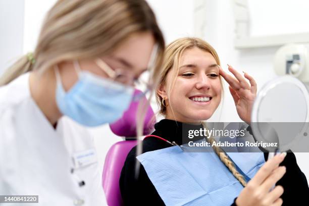 woman looking at her teeth after treatment. - pick tooth photos et images de collection