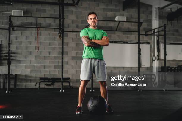 gym portrait of confident young man with medicine ball - running shorts stock pictures, royalty-free photos & images