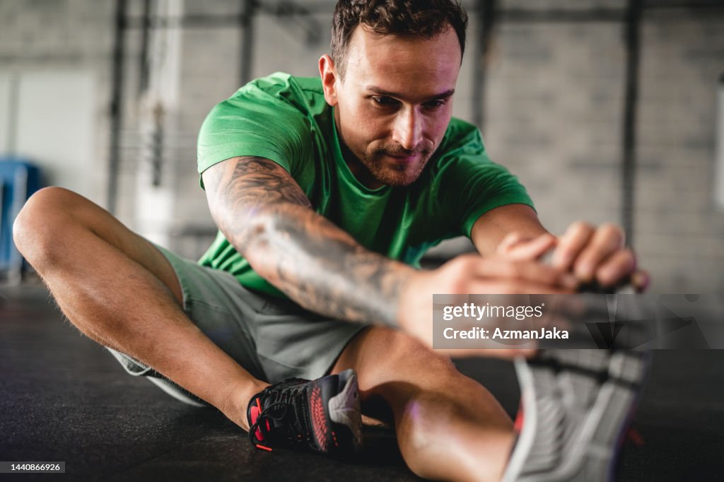 Close-Up of Focused Male Athlete Stretching at Gym