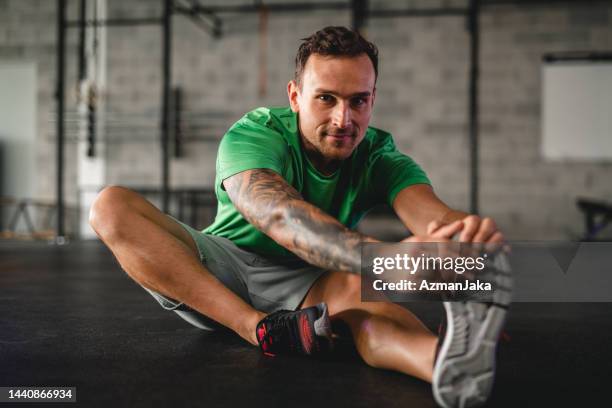 fiducioso giovane atleta maschio stretching in palestra - tendine del ginocchio foto e immagini stock