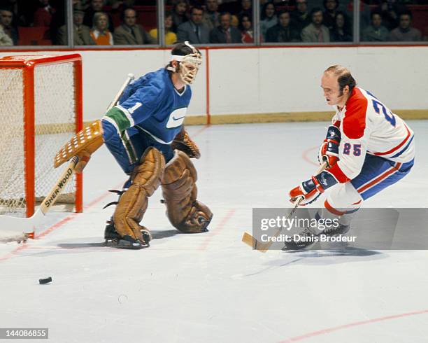 Dunc Wilson of the Vancouver Canucks pokes the puck away from Jacques Lemaire of the Montreal Canadiens Circa 1972 at the Montreal Forum in Montreal,...