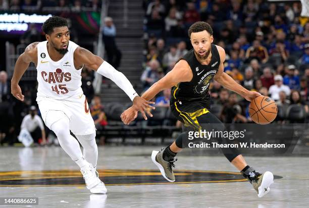 Stephen Curry of the Golden State Warriors dribbles the ball past Donovan Mitchell of the Cleveland Cavaliers in the third of an NBA basketball game...