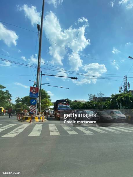 image of indian travellers waiting at zebra crossing, motorbikes, lorries, cars and rickshaws behind black and white striped pedestrian crossing waiting for stoplight to change pass, new delhi, india - city sensors stock pictures, royalty-free photos & images