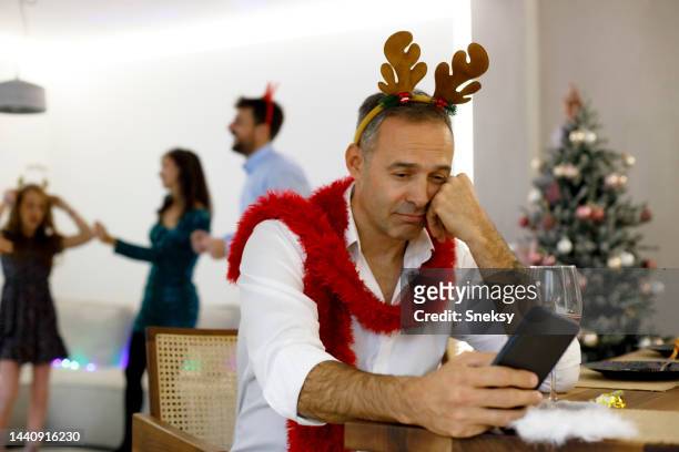 a sad man is waiting for a message on the phone for the new year - seasonal sadness stock pictures, royalty-free photos & images