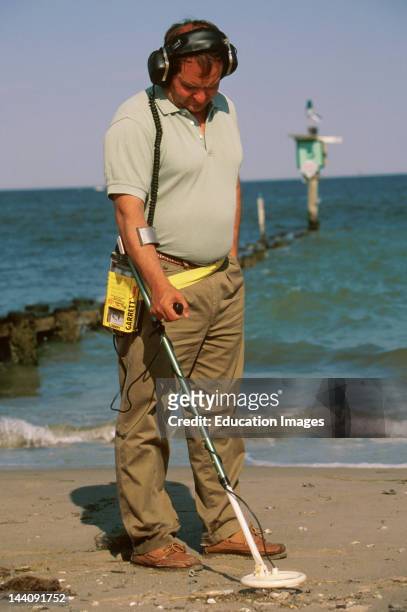 Virginia, Chesapeake Bay, Man On Beach, Using Metal Detector To Look For Treasure.