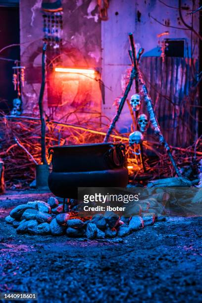 halloween concept.horrible old witch brews witchcraft in her cauldron surrounded by magical blue light. - witch wand stock pictures, royalty-free photos & images