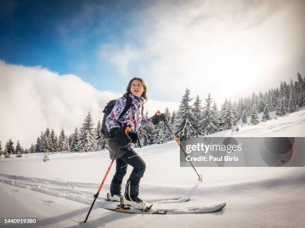 fully equipped woman enjoying ski touring off the track during one cold afternoon on the mountain, copy space - female skier stockfoto's en -beelden