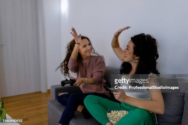 une belle jeune femme joue à des jeux vidéo avec sa meilleure amie. - remote controlled photos et images de collection