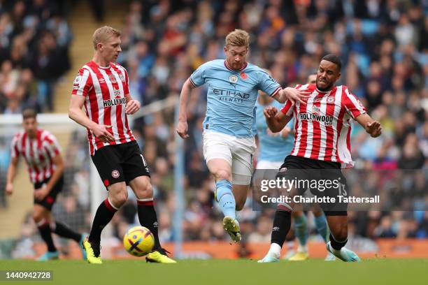 Kevin De Bruyne of Manchester City is challenged by Ben Mee and Mathias Zanka Jorgensen of Brentford during the Premier League match between...