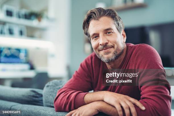 sorridente uomo di mezza età che gode di tempo rilassante a casa - self satisfaction foto e immagini stock