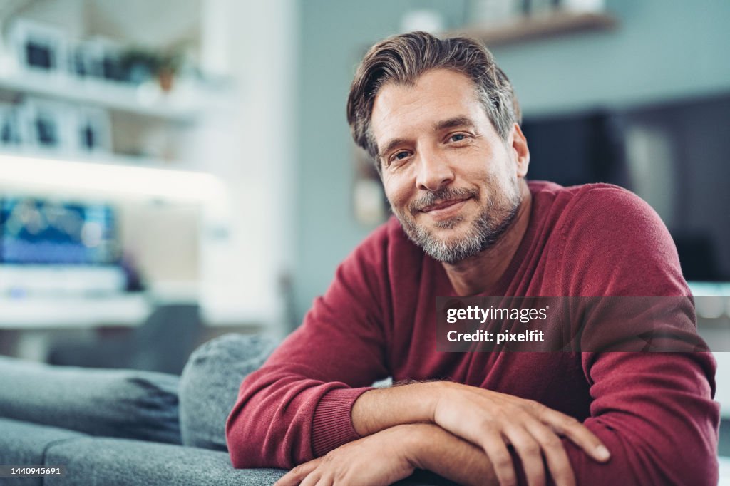 Smiling middle aged man enjoying relaxing time at home