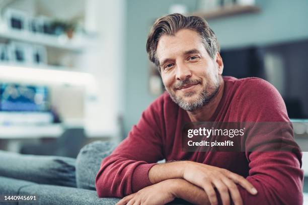 smiling middle aged man enjoying relaxing time at home - men imagens e fotografias de stock