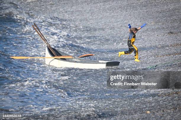 Fisherwomen leaps from her boat while returning to shore after checking her lines during sunny weather at Chesil Cove, on November 12, 2022 in...