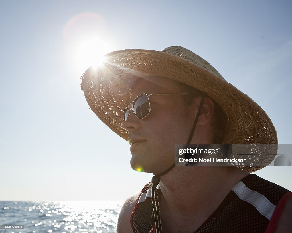 A man wears a hat and sunglasses while at sea