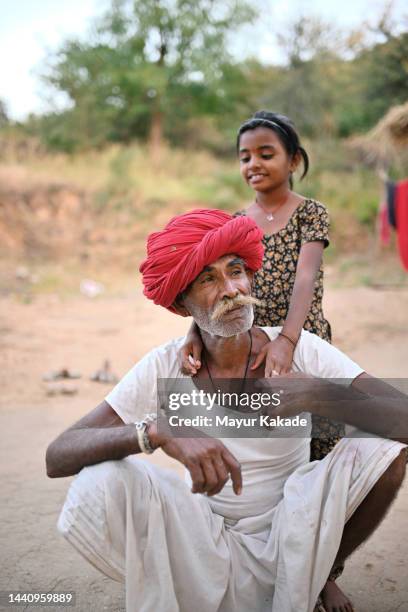 rural scene of a small girl embracing her grandfather from back - rajasthani youth stock pictures, royalty-free photos & images