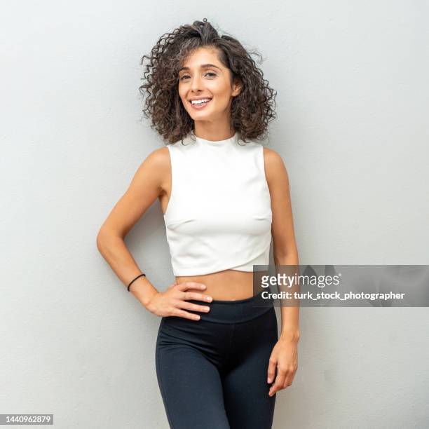 portrait of beautiful curly-haired woman in front of the wall - mature female models stock pictures, royalty-free photos & images