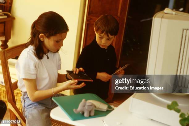 Year Old Girl And 6 Year Old Boy Using Cd On Home Computer.