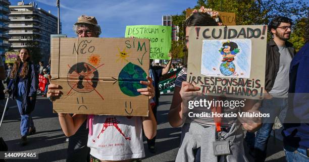 Demonstrators chant and hold placards at the rally convened by the Coalition "Unir contra o Fracasso Climático" , which brings together several...