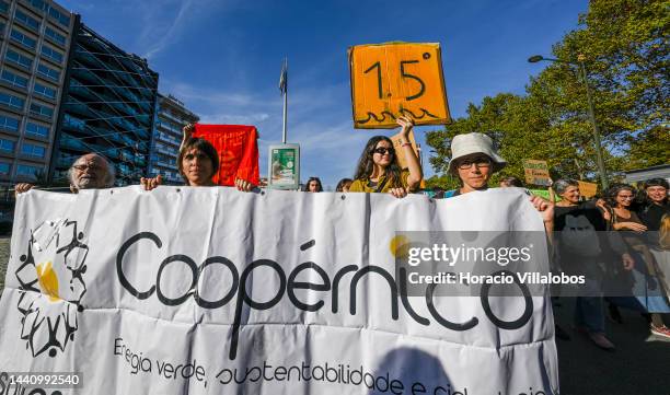 Demonstrators chant and holding placards as they march behind a banner at the rally convened by the Coalition "Unir contra o Fracasso Climático" ,...