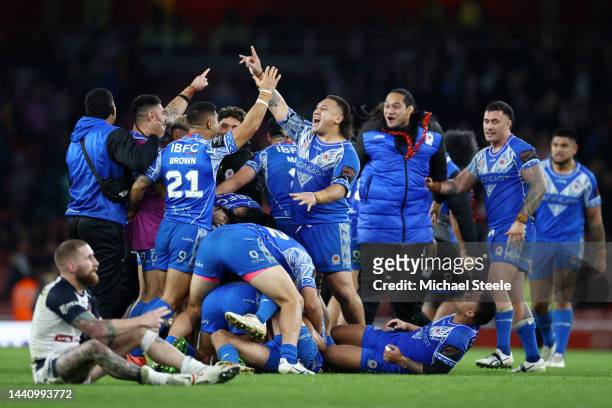 Josh Papalii of Samoa celebrates with teammates following their side's victory as Sam Tomkins of England looks dejected in the Rugby League World Cup...
