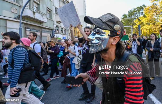 Demonstrators, one of them wearing a Guy Fawkes mask, chant and hold placards at the rally convened by the Coalition "Unir contra o Fracasso...