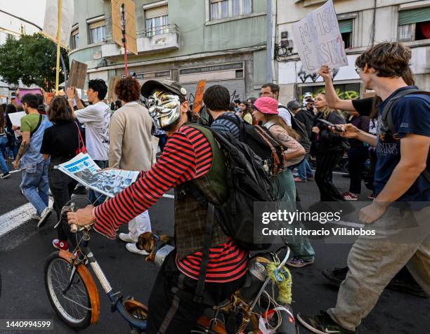 Demonstrators, one of them wearing a Guy Fawkes mask, chant and hold placards at the rally convened by the Coalition "Unir contra o Fracasso...