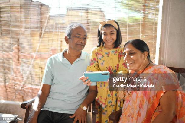 granddaughter showing smart phone to grandparents and smiling - indian grandparents stock pictures, royalty-free photos & images