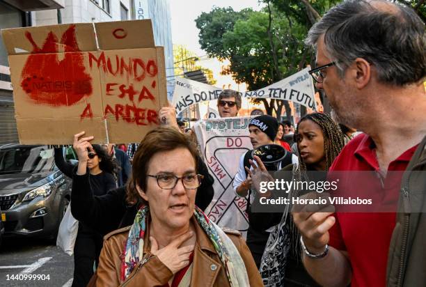 Demonstrators chant and hold placards at the rally convened by the Coalition "Unir contra o Fracasso Climático" , which brings together several...