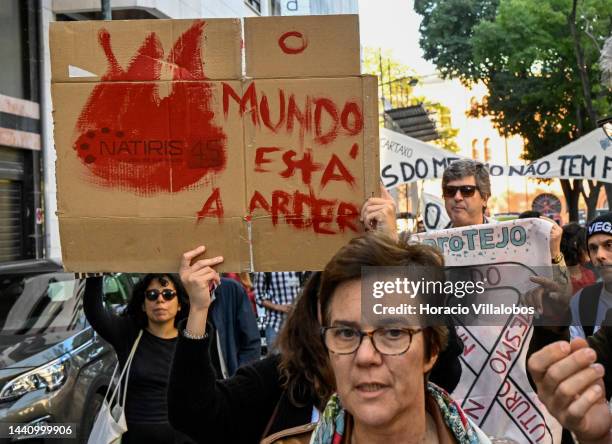 Demonstrators chant and hold placards at the rally convened by the Coalition "Unir contra o Fracasso Climático" , which brings together several...