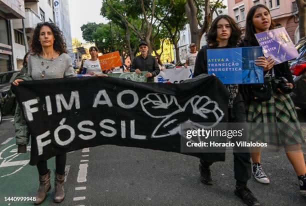 Demonstrators chant and hold placards as they walk behind a banner at the rally convened by the Coalition "Unir contra o Fracasso Climático" , which...