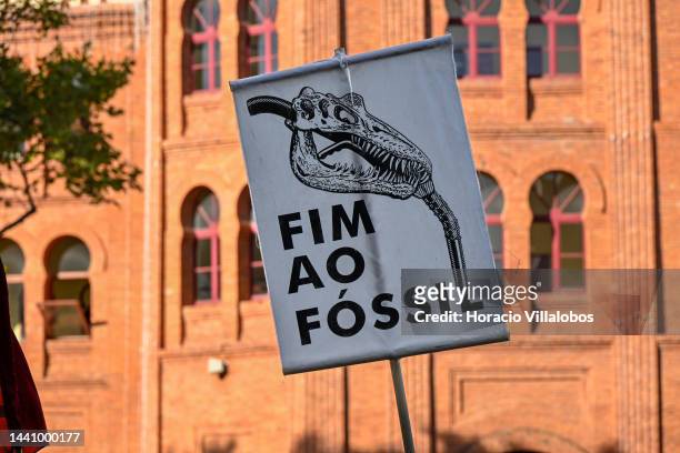 Placard showing a fossil head as a gasoline hose is hoisted by a demonstrator at the rally convened by the Coalition "Unir contra o Fracasso...
