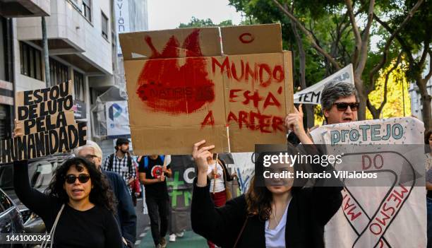 Demonstrators chant and hold placards at the rally convened by the Coalition "Unir contra o Fracasso Climático" , which brings together several...