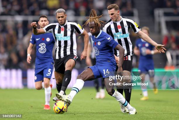 Trevoh Chalobah of Chelsea is challenged by Joelinton and Chris Wood of Newcastle United during the Premier League match between Newcastle United and...