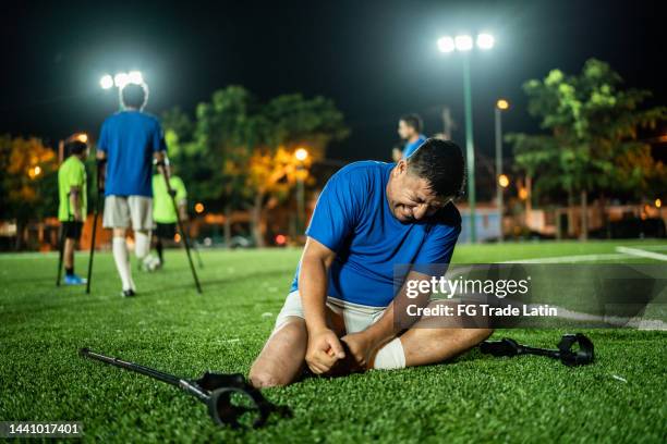 mid adult amputee feeling pain in ankle on soccer field - league all access stock pictures, royalty-free photos & images