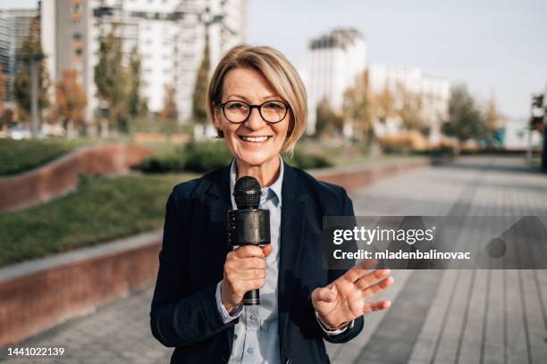 female reporter on city street during live broadcast - correspondence stockfoto's en -beelden