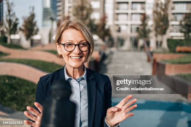 female reporter on city street during live broadcast - entrevista imagens e fotografias de stock