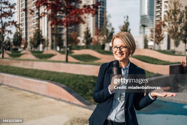 female reporter on city street during live broadcast - reportage portrait stock pictures, royalty-free photos & images