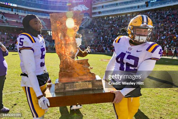 Jay Ward and Lane Blue of the LSU Tigers carry The Boot trophy off the field after a game against the Arkansas Razorbacks at Donald W. Reynolds...