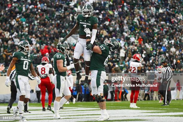 Jayden Reed of the Michigan State Spartans is lifted by teammate J.D. Duplain after scoring a touchdown in the second half of a game against the...