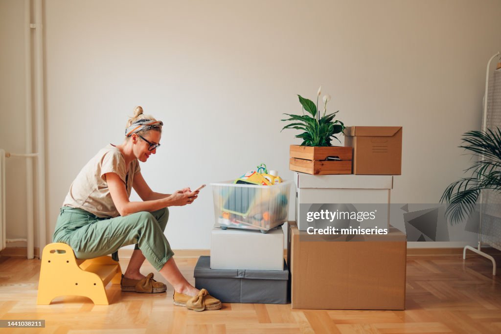 Happy Woman Using A Mobile Phone In New Home