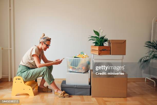 happy woman using a mobile phone in new home - zoom out stock pictures, royalty-free photos & images