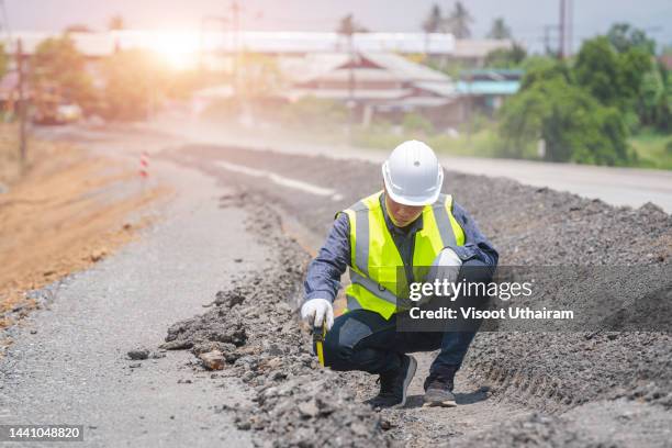 engineer worker making measuring with equipment at construction site during road works. - tarmac worker stock pictures, royalty-free photos & images