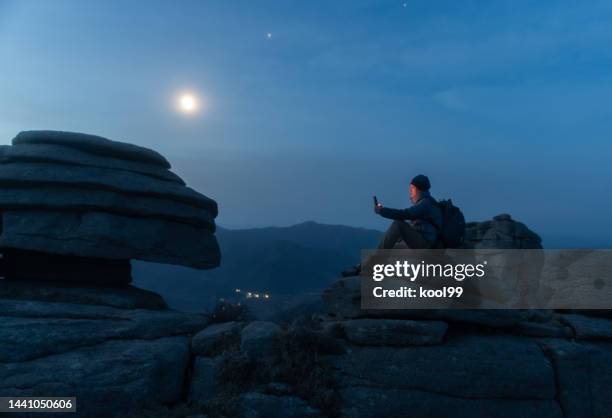 hikers reading in the moonlight on the mountain - moonlight stock pictures, royalty-free photos & images