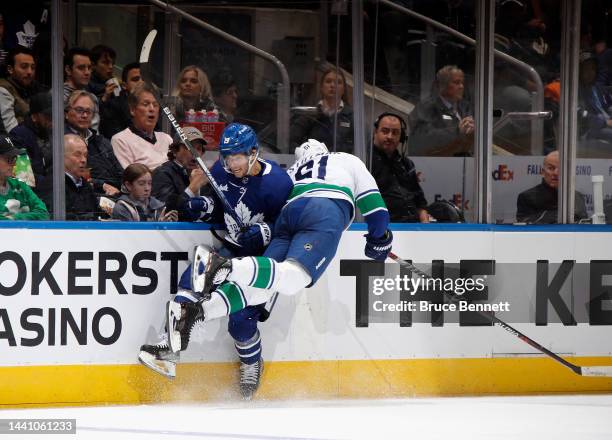 Riley Stillman of the Vancouver Canucks checks Calle Jarnkrok of the Toronto Maple Leafs into the boards during the second period at the Scotiabank...
