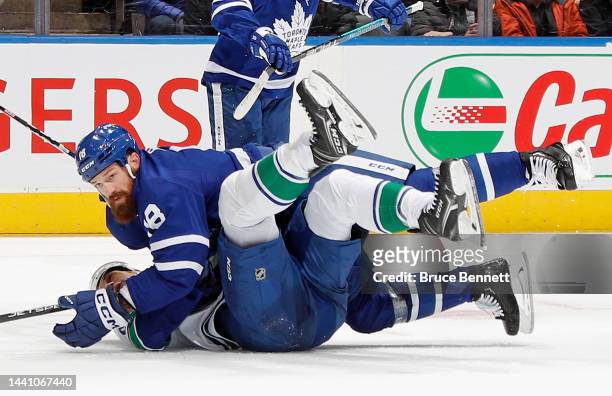 Jordie Benn of the Toronto Maple Leafs and Dakota Joshua of the Vancouver Canucks gets tangled up during the third period at the Scotiabank Arena on...