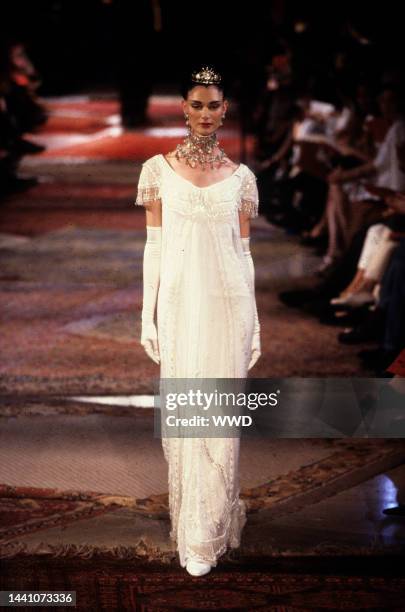 Floor-length white cap-sleeve dress with lace and beaded fringe detailing worn with jeweled collar necklace, evening gloves and tiara in the Givenchy...