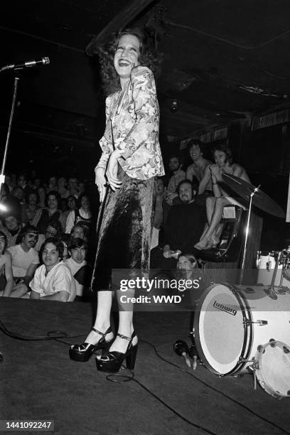 Actress and singer Bette Midler, wearing a velvet skirt and platform shoes, performing for a crowd of gay men at the Continental Club bath house in...