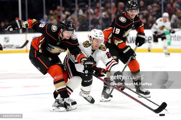 John Klingberg of the Anaheim Ducks battles Philipp Kurashev of the Chicago Blackhawks for a loose puck during the third period of a game at Honda...