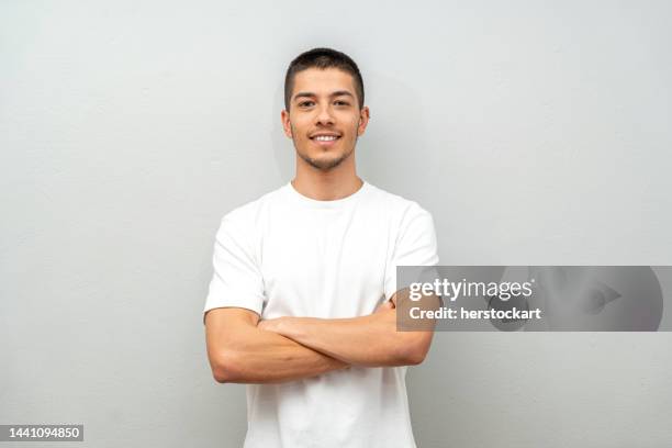 portrait of young man in front of gray wall - arms crossed stock pictures, royalty-free photos & images